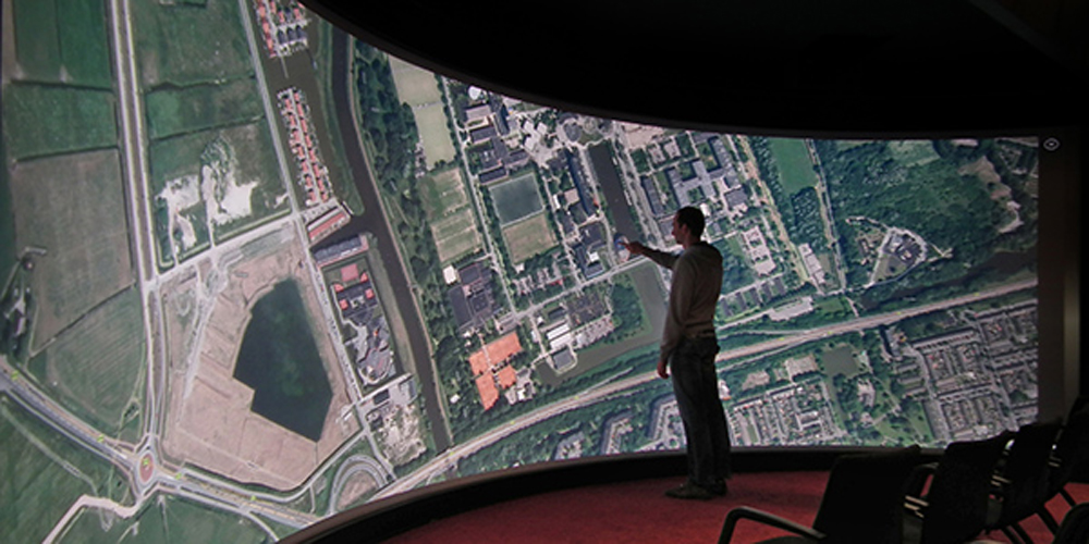 A photo of a person standing in front of a huge digital map